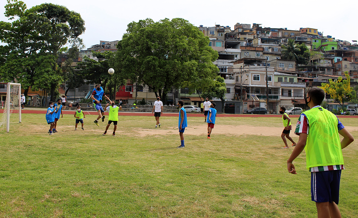 As crianças e jovens realizam atividades esportivas no campo de futebol