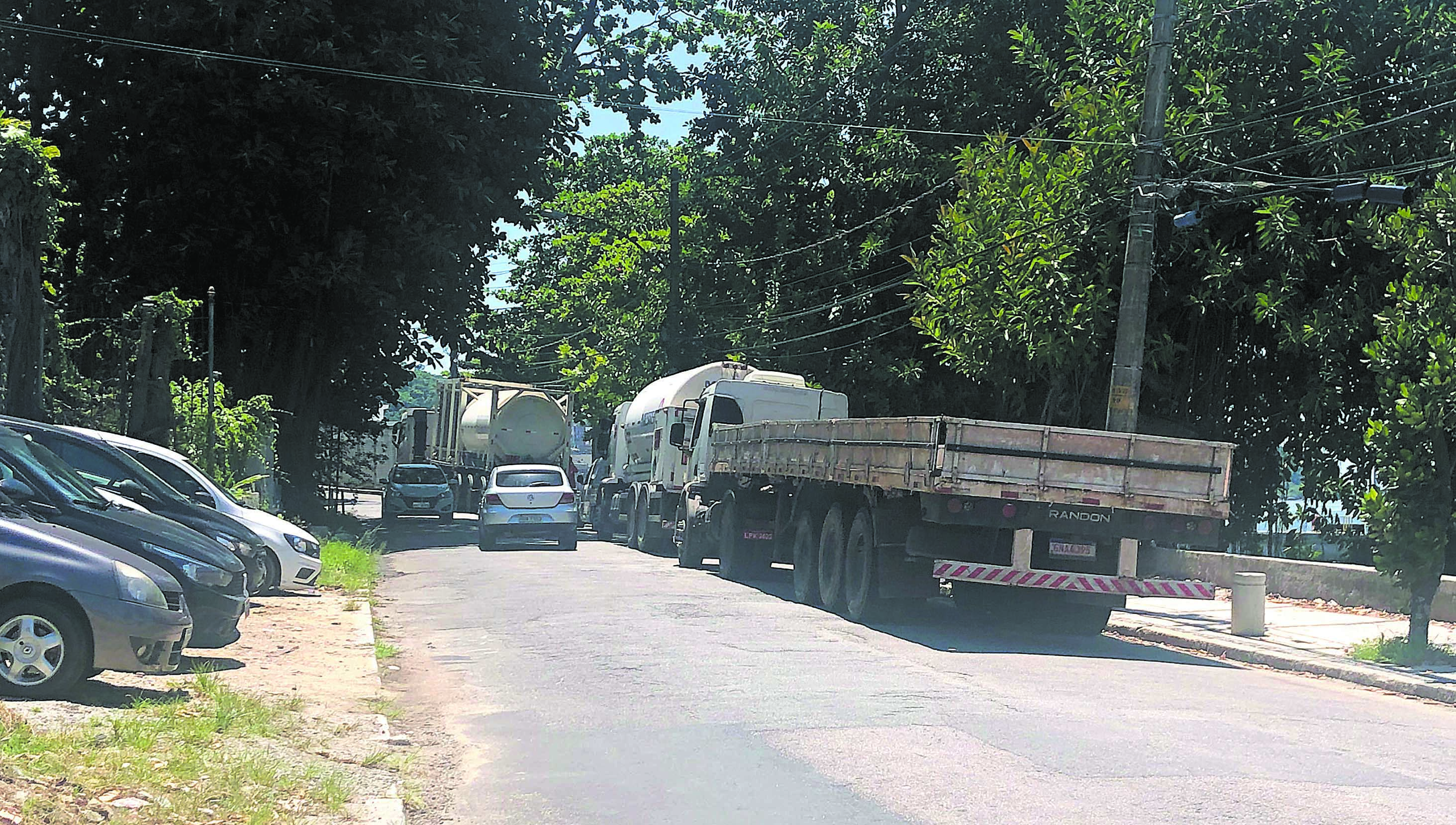 Caminhões esperando balsa para a Ilha D´Água (Transpetro) estacionados na via de rolamento próximos a uma curva perigosa na Praia Congonhas do Campo
