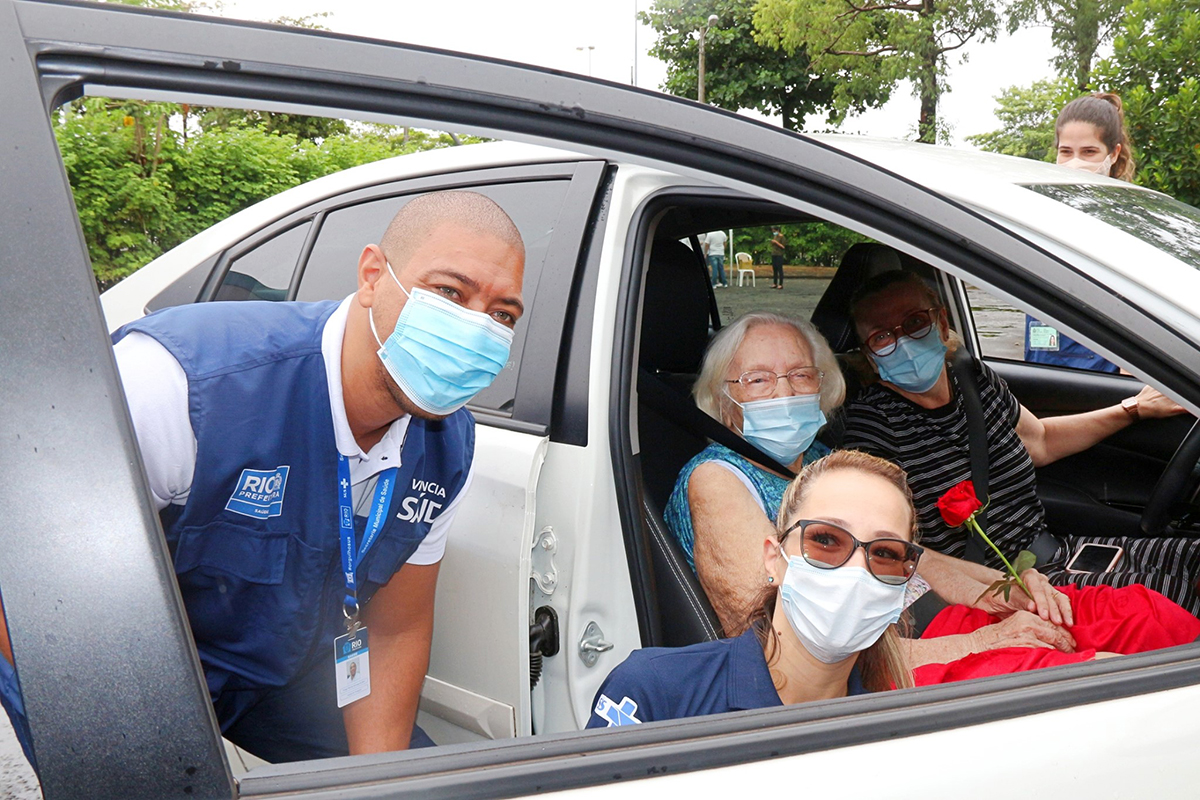 Equipes da área de saúde da prefeitura entregam rosa a idosa após imunização