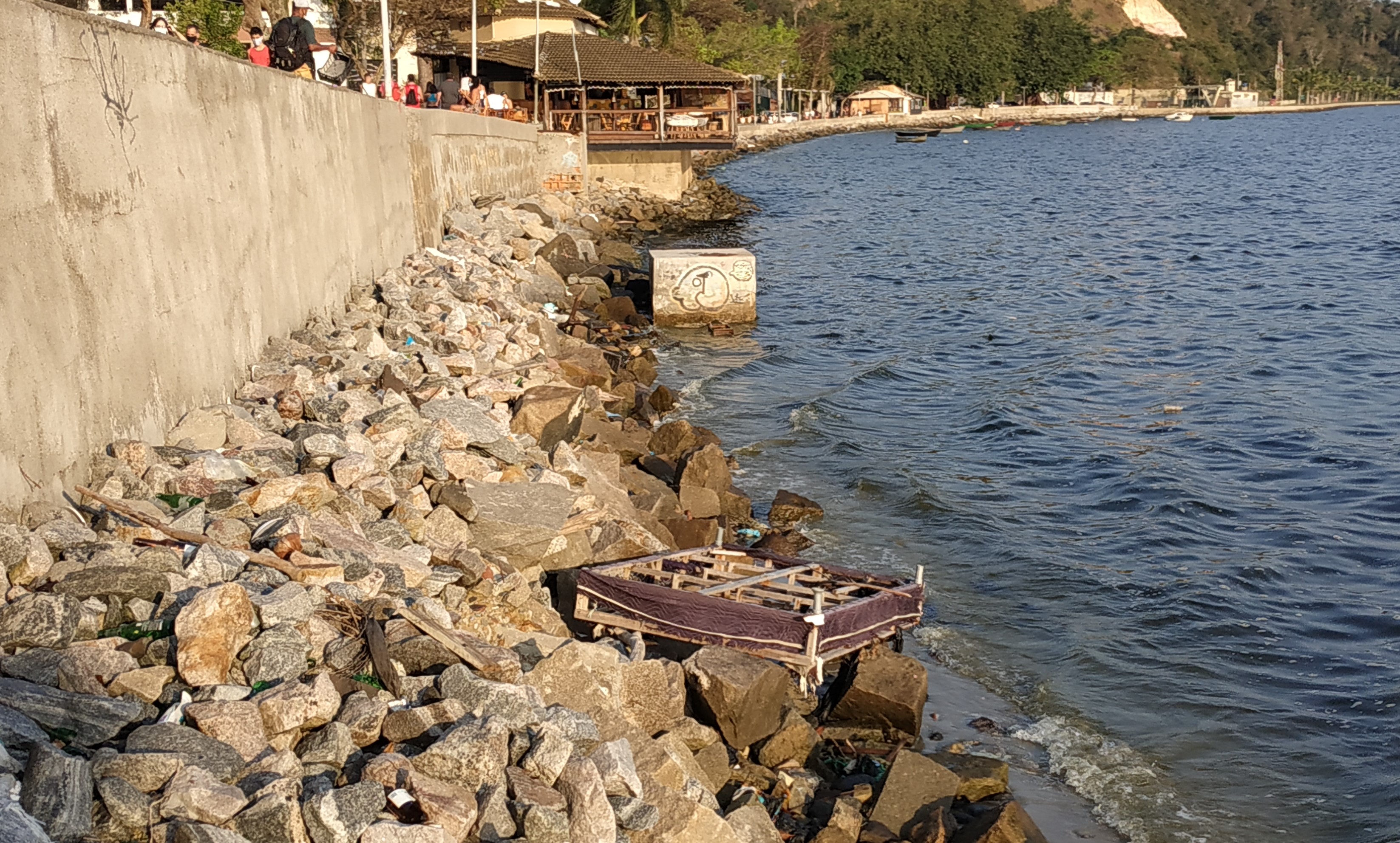 Os restos de uma cama de casal vieram com a maré e está preso nas pedras de contenção da Praia da Bica
