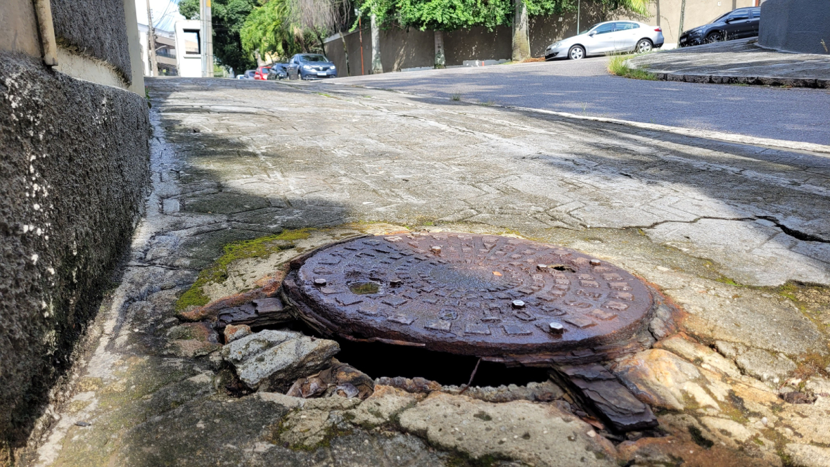 Buraco na calçada e bueiro corroído pela ferrugem na Rua Antônio Nascimento, 41, Jardim Guanabara
