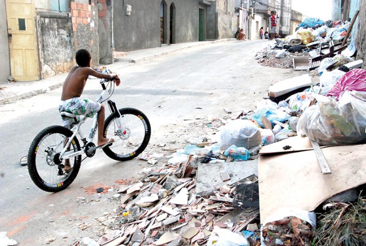 Menino brinca com a bicicleta em meio ao lixo na Rua Zaquia Jorge, nos Bancários