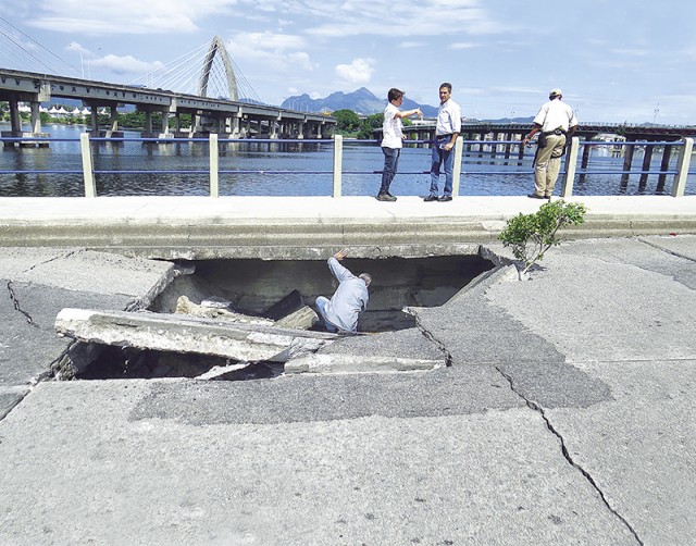 Técnicos da prefeitura examinam o buraco que se formou na pista com o deslocamento de pesadas placas de concreto 