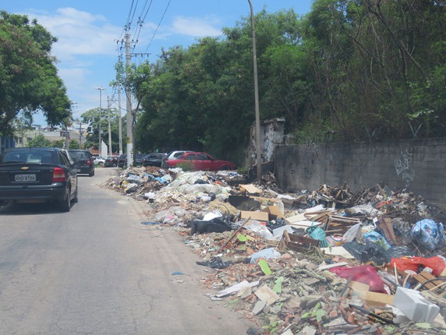 Na pista de acesso a Tubiacanga, próximo ao posto do Detran, lixo acumulado ocupa a calçada e parte da via