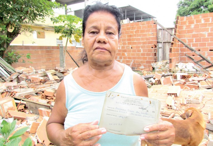 Na frente dos escombros da sua casa, Yvonete mostra documento do imóvel