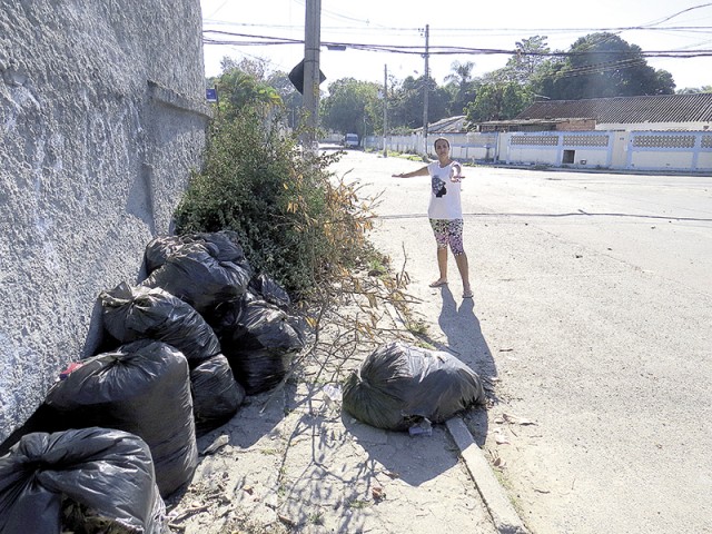 Sacos de lixo e galhos de árvore se acumulam junto ao muro da Escola Estadual Anita Garibaldi 