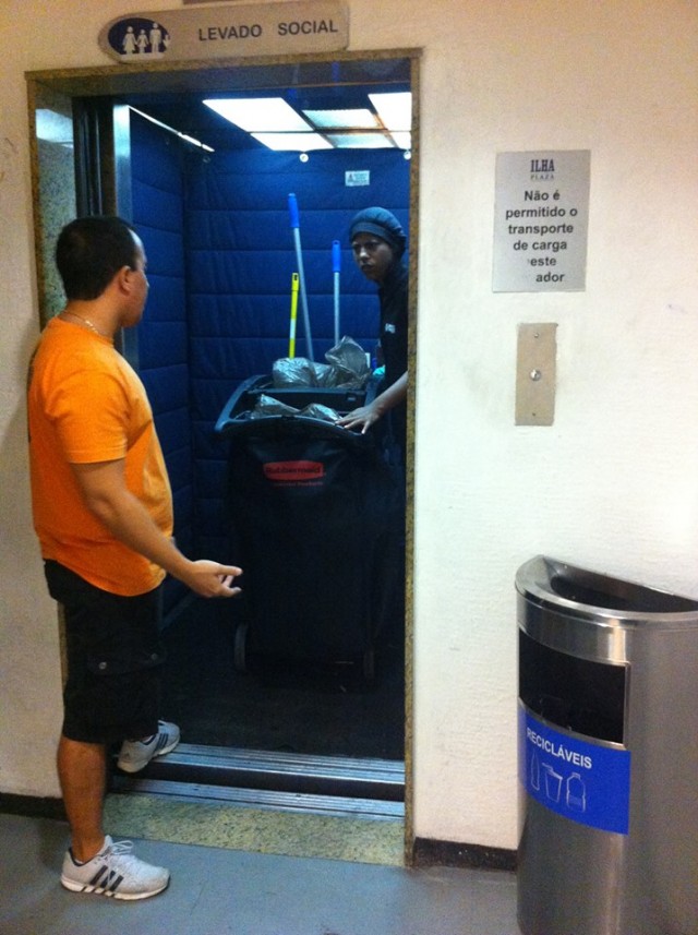 Carrinho de lixo sendo transportado no elevador social