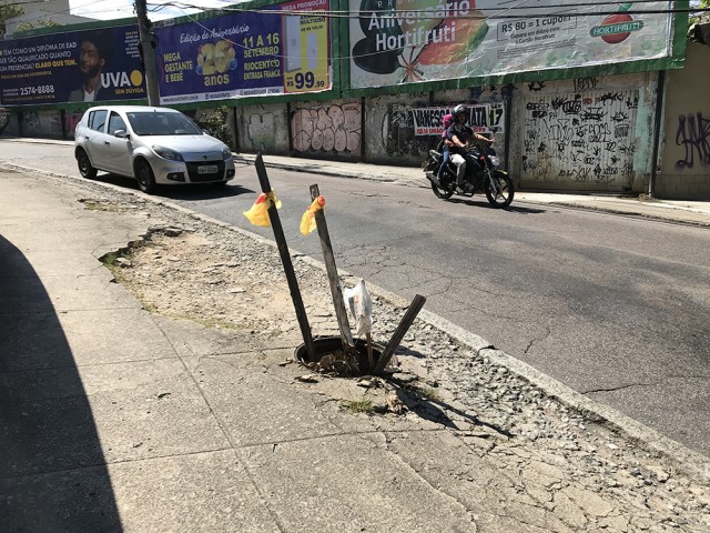 Pedaços de madeiras sinalizam um bueiro sem tampa na calçada da Rua Luís Belart, no Jardim Guanabara